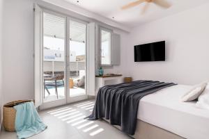 a white bedroom with a bed and a balcony at Quartano Suites by Heliessa, Adults Only in Naousa