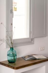 a glass vase sitting on a counter with a book at Quartano Suites by Heliessa, Adults Only in Naousa