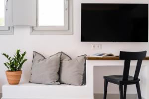 a couch with two pillows and a tv on a wall at Quartano Suites by Heliessa, Adults Only in Naousa