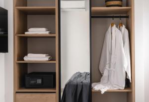 a closet with white clothes and a mirror at Quartano Suites by Heliessa, Adults Only in Naousa