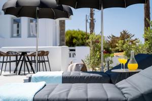 a patio with two couches and an umbrella at Quartano Suites by Heliessa, Adults Only in Naousa