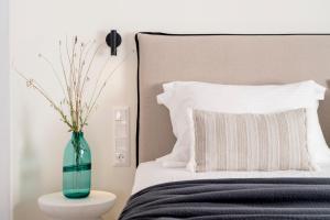 a green vase sitting on a table next to a bed at Quartano Suites by Heliessa, Adults Only in Naousa