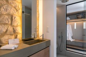 a bathroom with a sink and a stone wall at Quartano Suites by Heliessa, Adults Only in Naousa