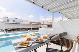 a table with two glasses of wine and food next to a swimming pool at Quartano Suites by Heliessa, Adults Only in Naousa