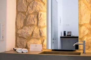 a bathroom with a sink with a stone wall at Quartano Suites by Heliessa, Adults Only in Naousa