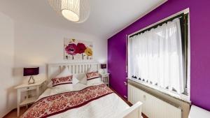 1 dormitorio con paredes de color púrpura y ventana grande en Ferienwohnung Seeblick I, en Schalkenmehren