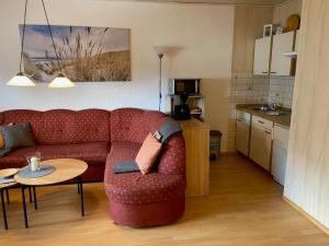 a living room with a red couch and a table at Ferienwohnung "Strandoase" in Burhave