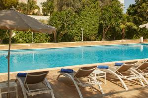 a group of chairs and an umbrella next to a swimming pool at Hotel Joan Miró Museum in Palma de Mallorca