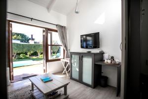 a living room with a tv and a table with a coffee table at Sixteen Guesthouse on Main in Hermanus