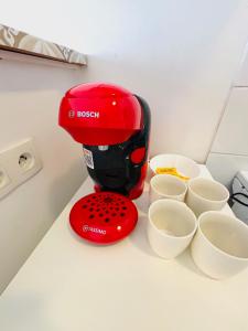 een rode mixer op een aanrecht naast kopjes bij Appartement rue Lecourbe in Parijs