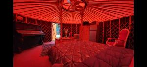 1 dormitorio rojo con cama y piano en La Yourte, en Vinassan
