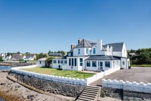 a large white house on the shore of the water at Aultbea Hotel in Achnasheen