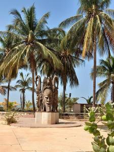 a statue of a head with palm trees in the background at VILLA TABARA HOTEL LA TERANGA Saly Senegal in Sali Poulang
