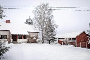 een met sneeuw bedekte tuin voor een rode schuur bij Metsäsydän huonemajoitus in Puumala +27 foto's