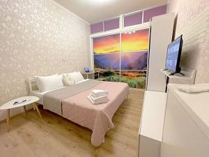 a bedroom with a bed and a tv and a window at Лавандовий світанок Однокімнатна квартира біля ЦУМу в центрі Полтави Мережа AlexApartments Документи для відряджень Безконтатне заселення 24-7 in Poltava +6 photos
