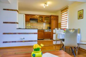 Una cocina con gabinetes de madera y una mesa con sillas. en Apartman Ozimice 2, en Bihać
