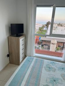 a bedroom with a television and a large window at Ático con vistas al mar y piscina privada in Vera