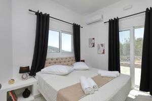 a bedroom with a large bed with black curtains at Villa Mirage Skopelos in Skopelos Town +35 photos