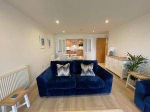 ein Wohnzimmer mit einer blauen Couch und einer Küche in der Unterkunft 30 Bredon Court Newquay Sea view in Newquay