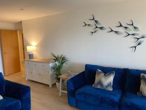 ein Wohnzimmer mit einem blauen Sofa und einem Tisch in der Unterkunft 30 Bredon Court Newquay Sea view in Newquay