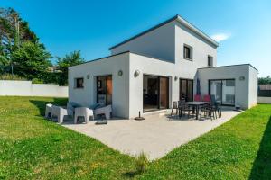 Clohars-CarnoëtにあるVilla des îles - A 350m de la plageの庭にパティオ付きの白い家
