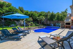 a patio with chairs and an umbrella next to a swimming pool at CASA MARGARETA in Dramalj