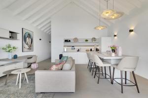 a white kitchen and living room with a table and chairs at Las Dunas with Stunning Sea View and Shared Pool in Kralendijk