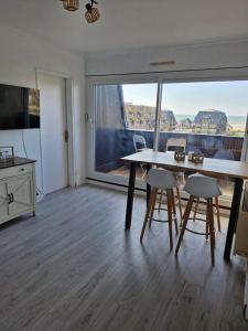 ein Wohnzimmer mit einem Tisch und Stühlen sowie einem großen Fenster in der Unterkunft Villers vue sur mer in Villers-sur-Mer