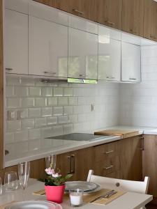 Ionian home في Exanthia: مطبخ مع دواليب بيضاء وطاولة مع كراسي