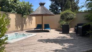 a hot tub with two chairs and an umbrella on a deck at Eco logde & spa in Châteaurenard