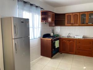 a kitchen with a stainless steel refrigerator and wooden cabinets at Katila Morro Coral in Espargos +14 photos