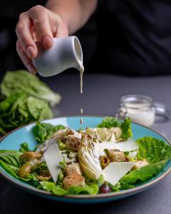 a person pouring sauce on a plate of salad at Glass House Retreat in Puddle Dock
