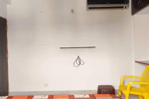 ティルパティにあるTiruchanoor Home stayの黄色い椅子と白い壁のあるリビングルーム +2枚の写真