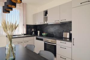 a kitchen with white cabinets and a table with chairs at Apartment B12 Balkon mit Naturblick & Nutzung der Wellness- & Aktivbereiche im Pine Hill Resort in Zirchow