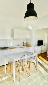 a white kitchen with a white table and chairs at Ile de Malvy in Saint-Simeux