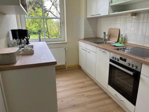 a kitchen with white cabinets and a sink and a stove at Ferienwohnung Rotbuche, 25517 in Weener