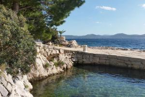 a stone wall next to a body of water at Kuća za odmor Island just for You- Island Sit in Murter