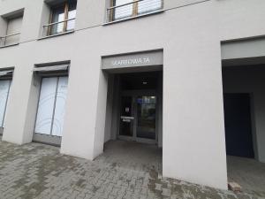 a white building with a sign on the door at City Lux Apartament Free Parking in Leszno