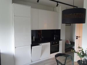 a kitchen with white cabinets and a black stove at City Lux Apartament Free Parking in Leszno +9 photos