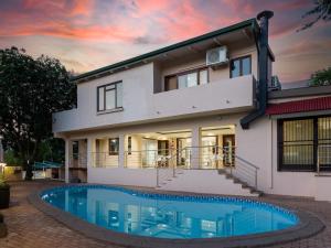 a house with a swimming pool in front of it at Global Village Guest House in Nelspruit