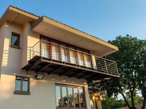 a house with a balcony on top of it at Global Village Guest House in Nelspruit