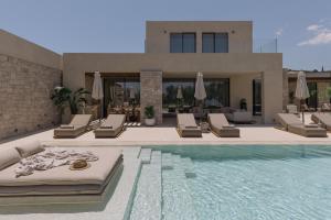 a swimming pool with chaise lounge chairs and a house at Valerozo Villas - Exclusive Beachside Experience in Amoudi +78 photos