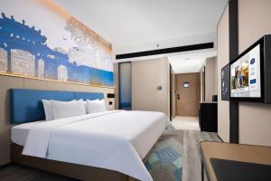 佛山市にあるHampton By Hilton Foshan Shunde Chencunの大きな白いベッドとテレビのある寝室