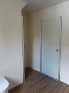 a bathroom with a toilet and a glass door at NEU! FeWo Bi´t Swaalvkenüst in Aurich