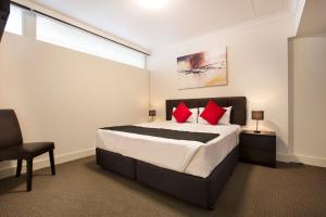 a bedroom with a large bed with red pillows at Enfield Hotel in Adelaide