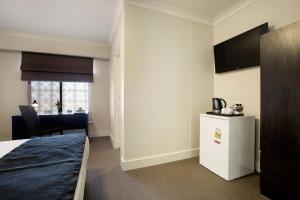 a hotel room with a bed and a tv at Enfield Hotel in Adelaide