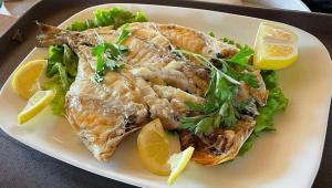 a plate of fish with lettuce and lemon slices at White Houses Complex in Fier +19 photos