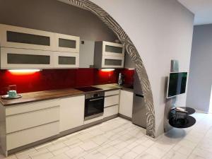 an archway in a kitchen with red and white cabinets at Central Vienna Apartment with unique 40m2 city garden & self check in in Vienna