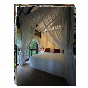 a bedroom with a white bed with curtains at Villa Sri Kampung in Kuah