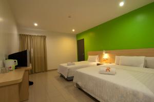 una habitación de hotel con 2 camas y una pared verde en T Hotel Changlun, en Changlun